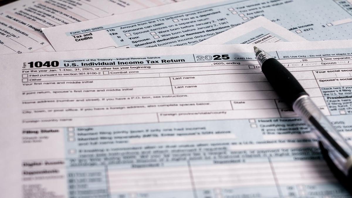 Person preparing a U.S. individual income tax return with forms and a pen